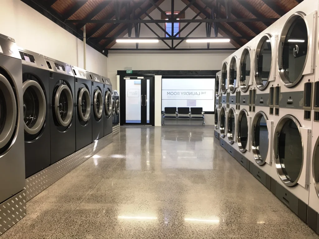 Rows of washers and dryers under a high timber ceiling at The Laundry Room