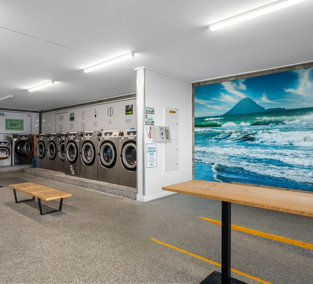 Washers, a bench and a large coastal mural at our Ōpōtiki laundromat