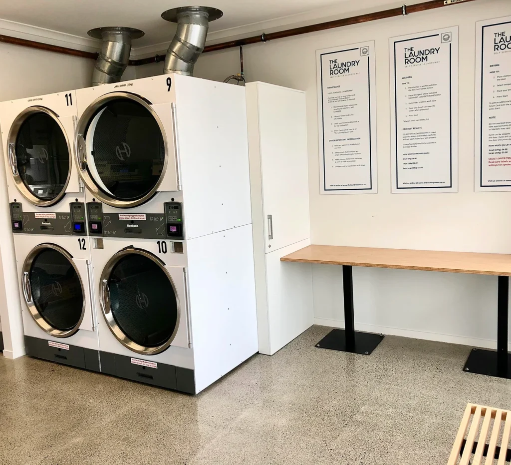 Numbered stacked dryers and a folding bench at our Raumati Beach laundromat