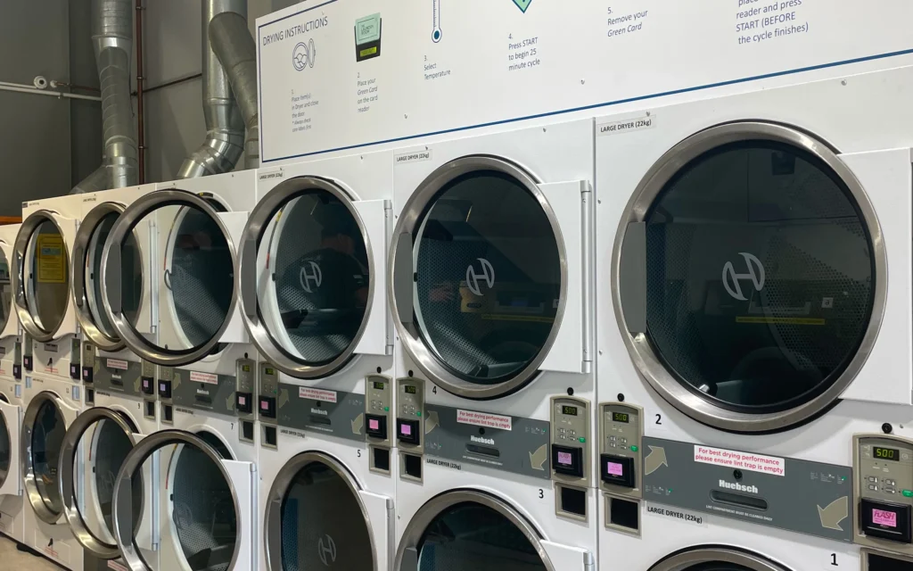 Stacked dryers with easy how-to signs at The Laundry Room Ōmokoroa