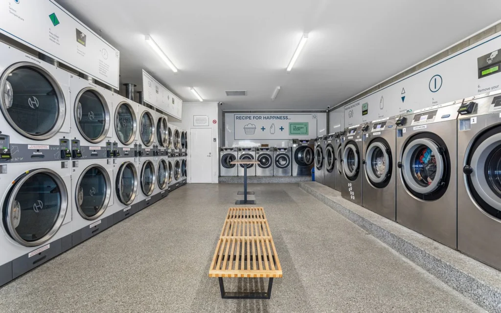 Long room of washers and dryers with a centre bench at The Laundry Room Ōpōtiki