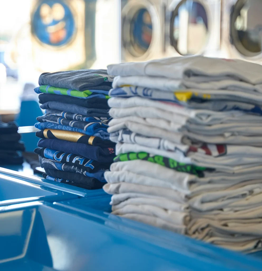 Stacks of folded clean clothes on a laundromat folding bench